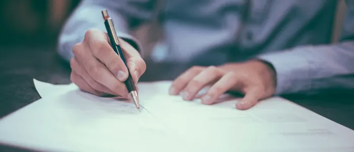 Person signing a printed agreement with a pen