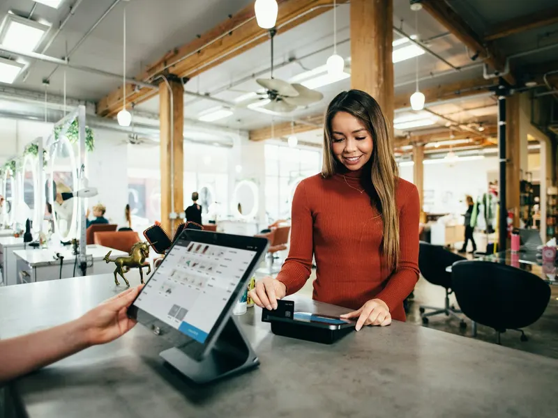 Salon owner taking a card payment from a customer at the counter